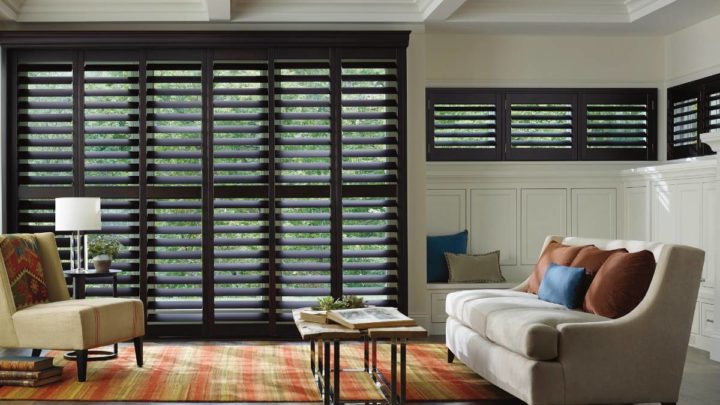 Contemporary living room with sofa, accent chair, and brown plantation shutters at Vignettes Home near Galena, IL, and Dubuque, IA