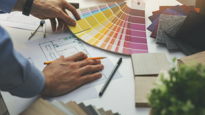 Man looking over color samples and a floor plan on a table.