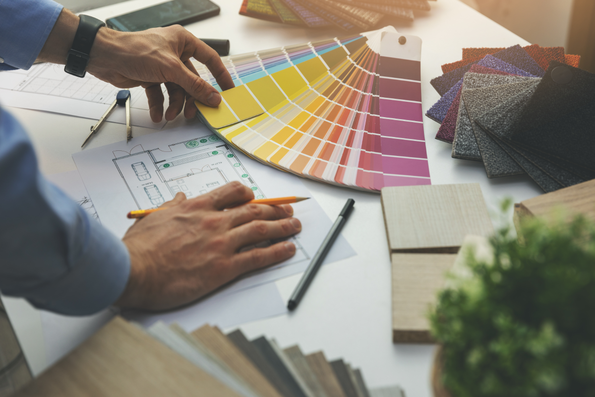 Man looking over color samples and a floor plan on a table.